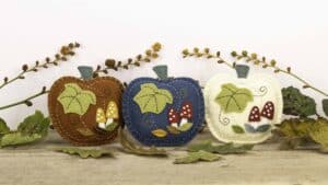 Embroidered felt pumpkin ornaments with little toadstools and autumn leaves