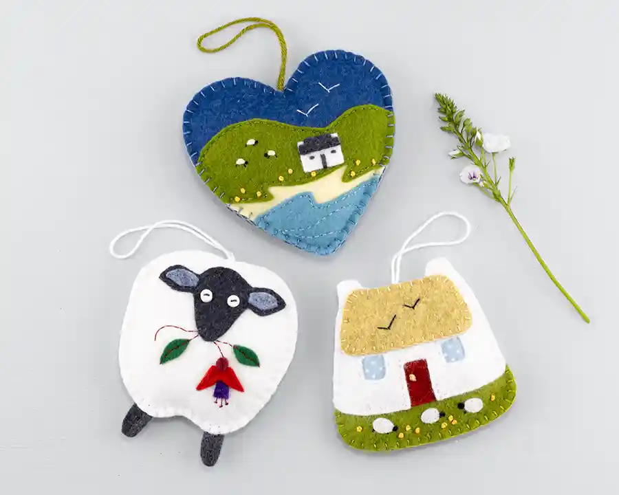 A set of 3 felt ornaments, including a sheep, a thatched cottage and a heart with an Irish landscape scene