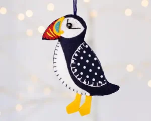 A black felt puffin ornament with black and white polka dot wing, colourful beak and dangling yellow feet