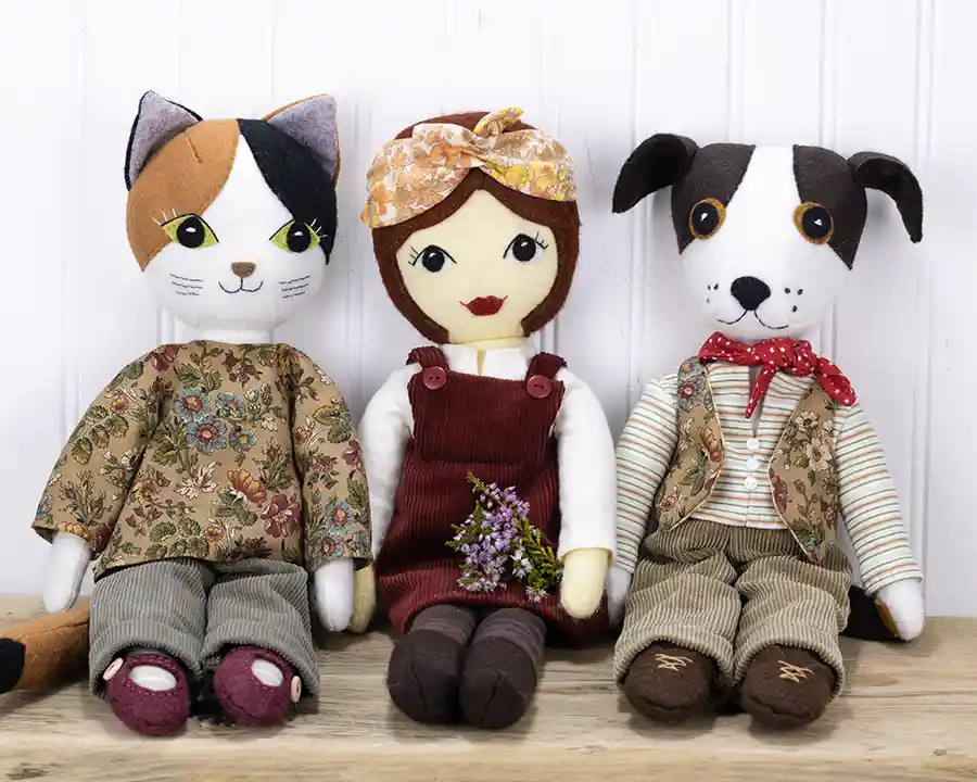 Tilly doll, Puffin the Cat and Toby the dog sitting on a wooden shelf, dressed in autumnal colours