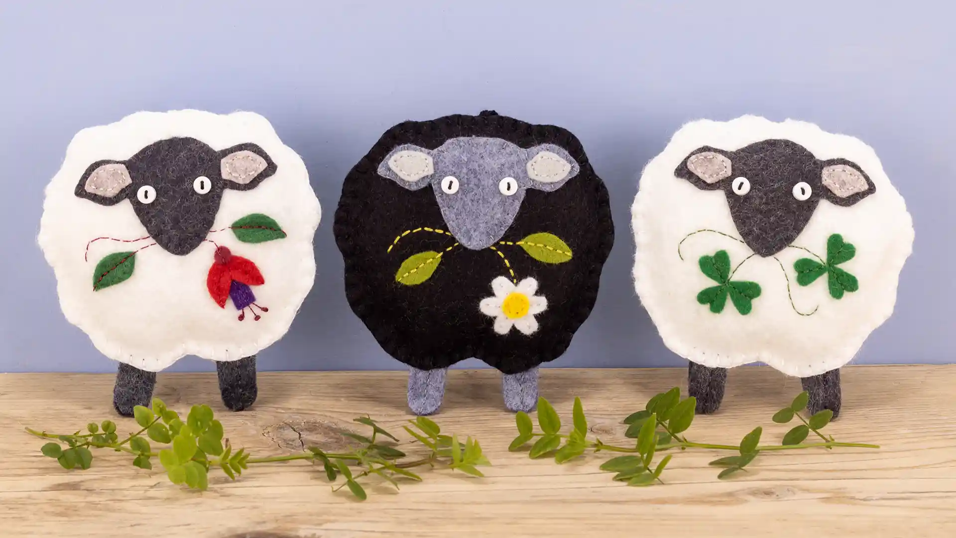 Three felt sheep ornaments. two white and one black, with Fuchsia, daisy and shamrock details.
