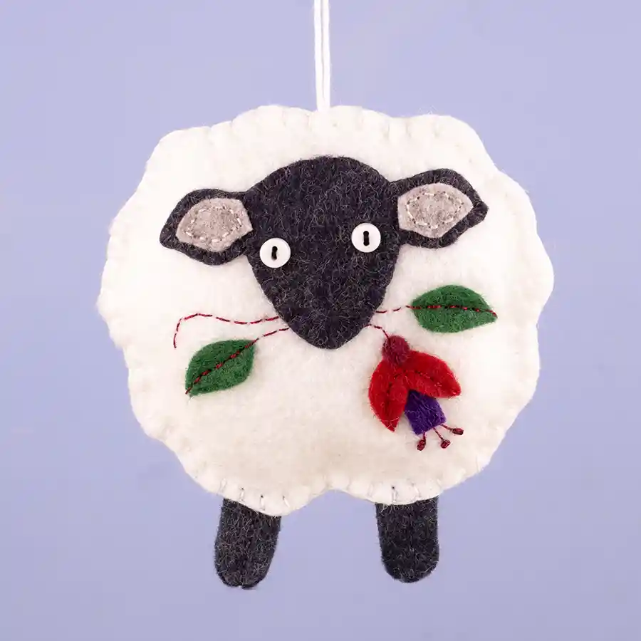 A white sheep felt ornament with dark grey head and legs, with a Fuchsia flower and leaves in its mouth.
