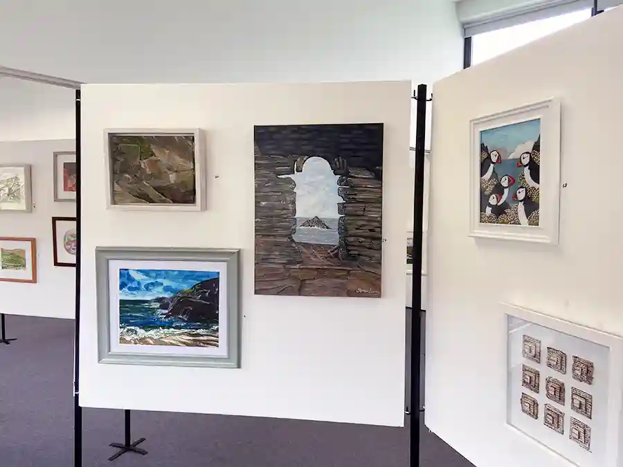 Display boards at an art exhibition showing my Atlantic puffins embroidery and some paintings.