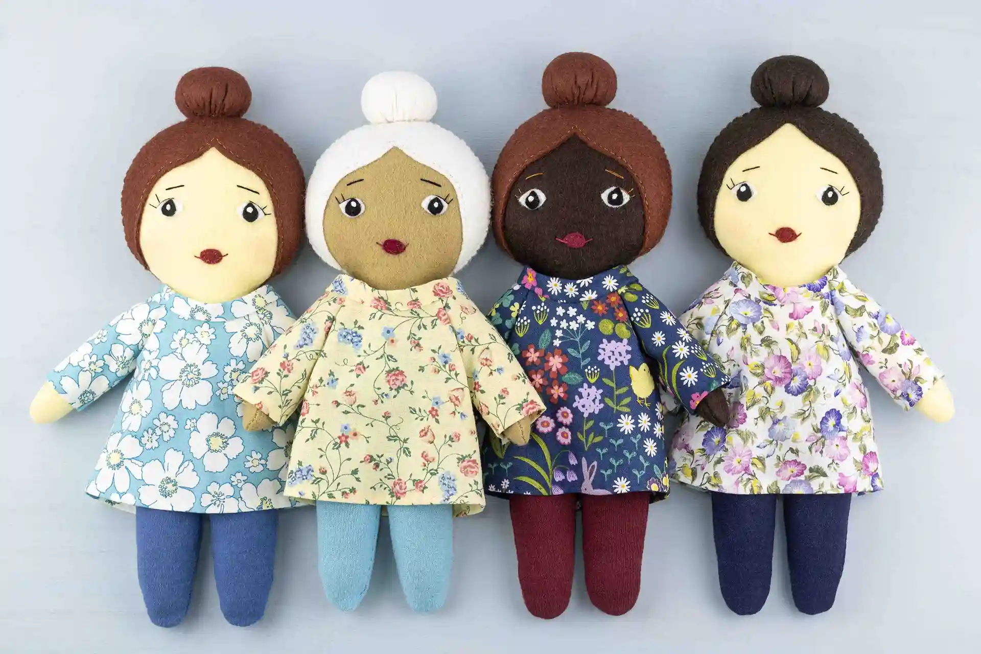 A row of four Daisy dolls with ballerina bun hairstyles, floral print tunics and matching tights.