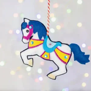 A white felt carousel horse with blue mane and tail and pink and yellow harness.