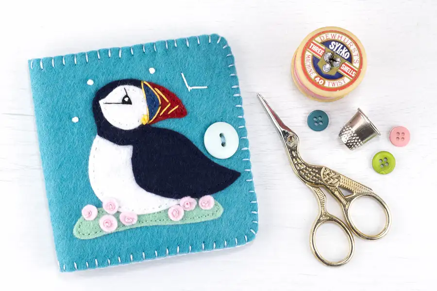 Puffin needle book shown with scissors, thread and buttons