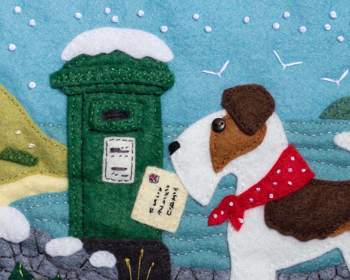 Fred the fox terrier posting a letter in a green Irish post box with a snowy coastal scene in the background.