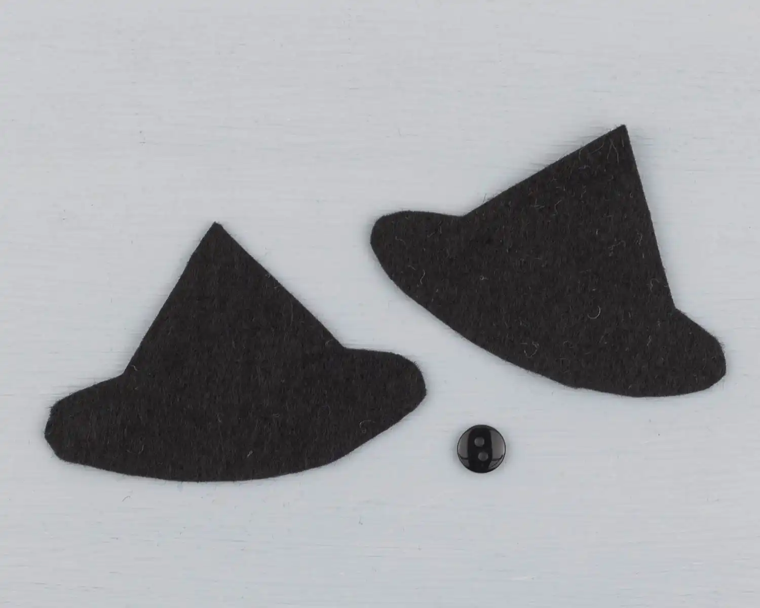 The two pieces of the owl's hat cut out, with a black button