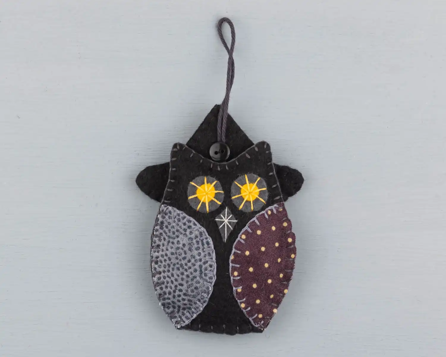 Front view of the owl showing a button stitched over the place where the hanging loop is sewn to the hat